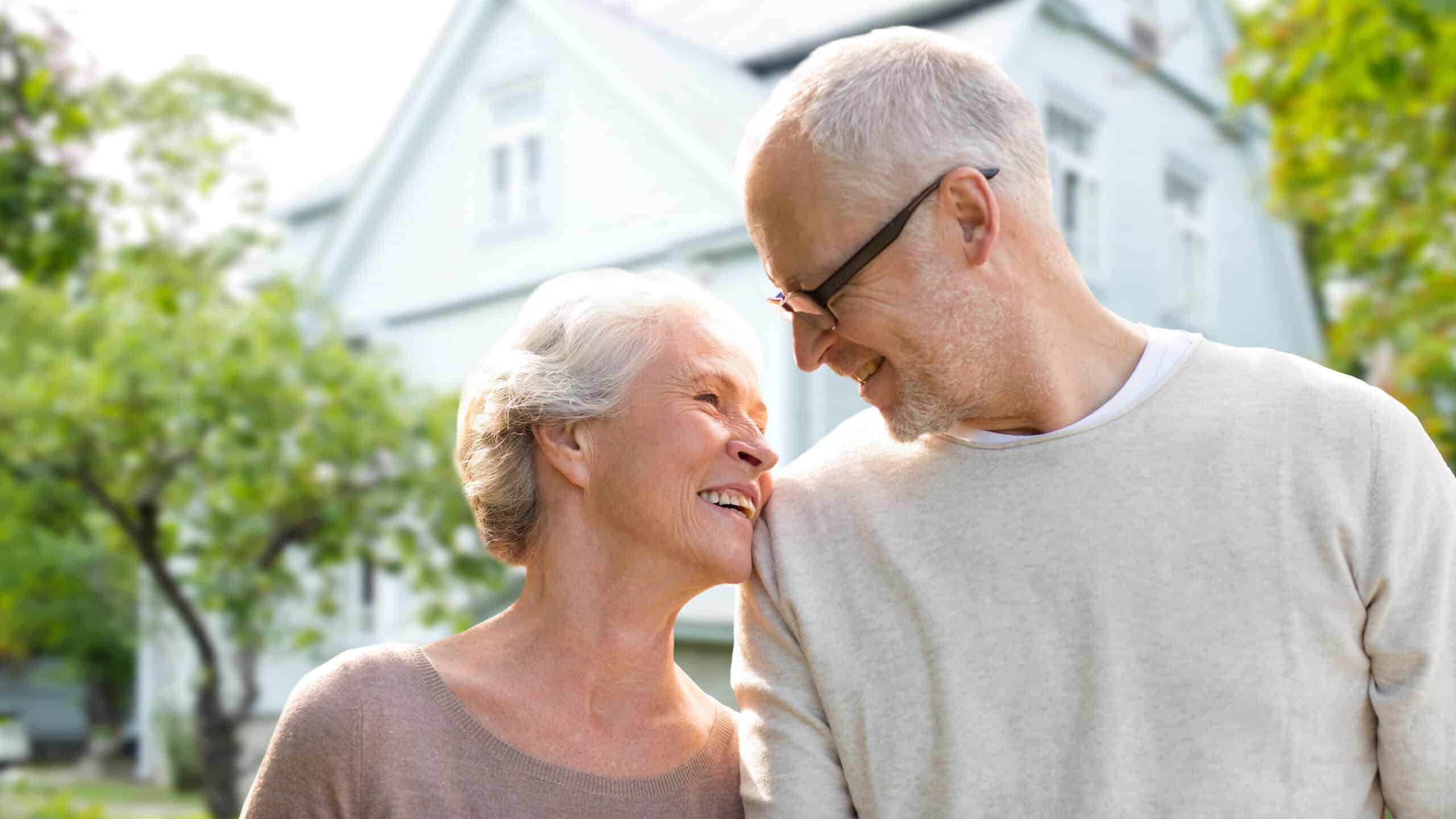 senior couple hugging over living house background